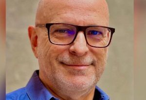 A photo of Angel Sanchez, voice actor, wearing a blue shirt.