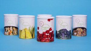 A row of cylinder packages with fruit and “Thrive Life” logos on the labels.