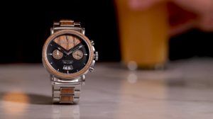 An Original Grain watch, with wooden accents, displayed on a counter with a pint of beer in the background.