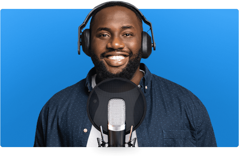 Voice actor wearing headphones and standing in front of a microphone.